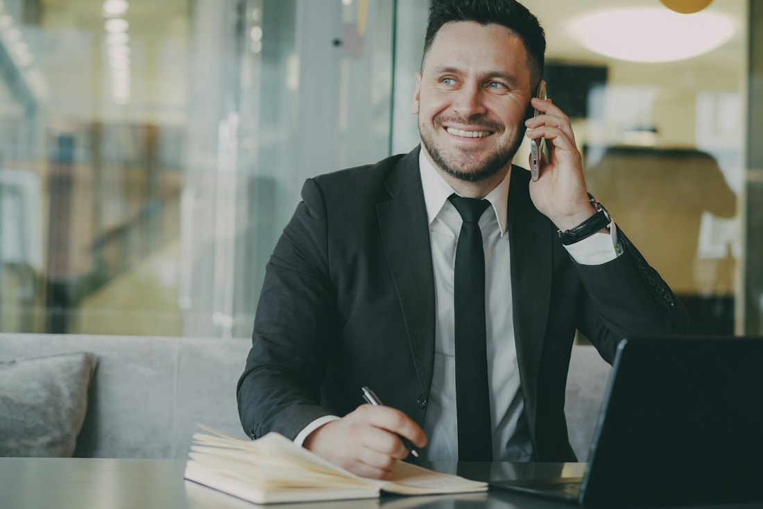 Smiling businessman on a phone call at his desk