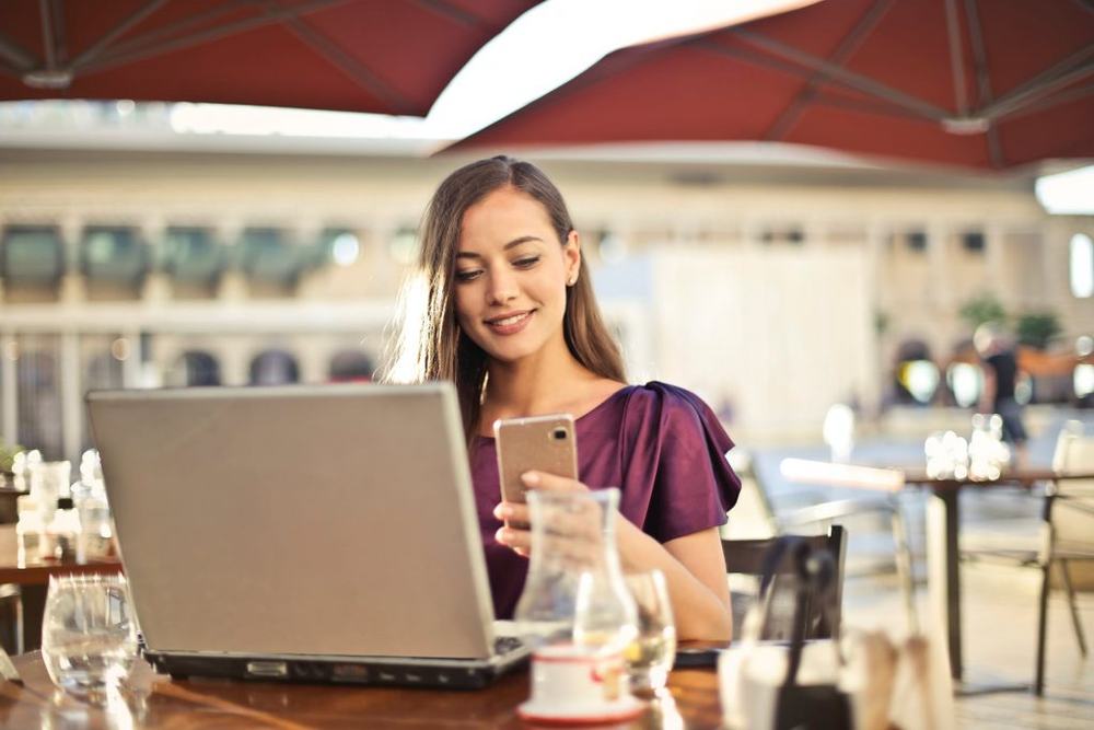 Woman working on a laptop and phone in a café