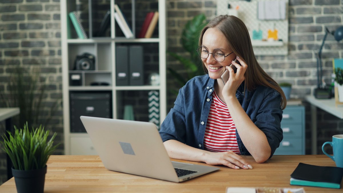 Smiling woman on the phone at her office desk